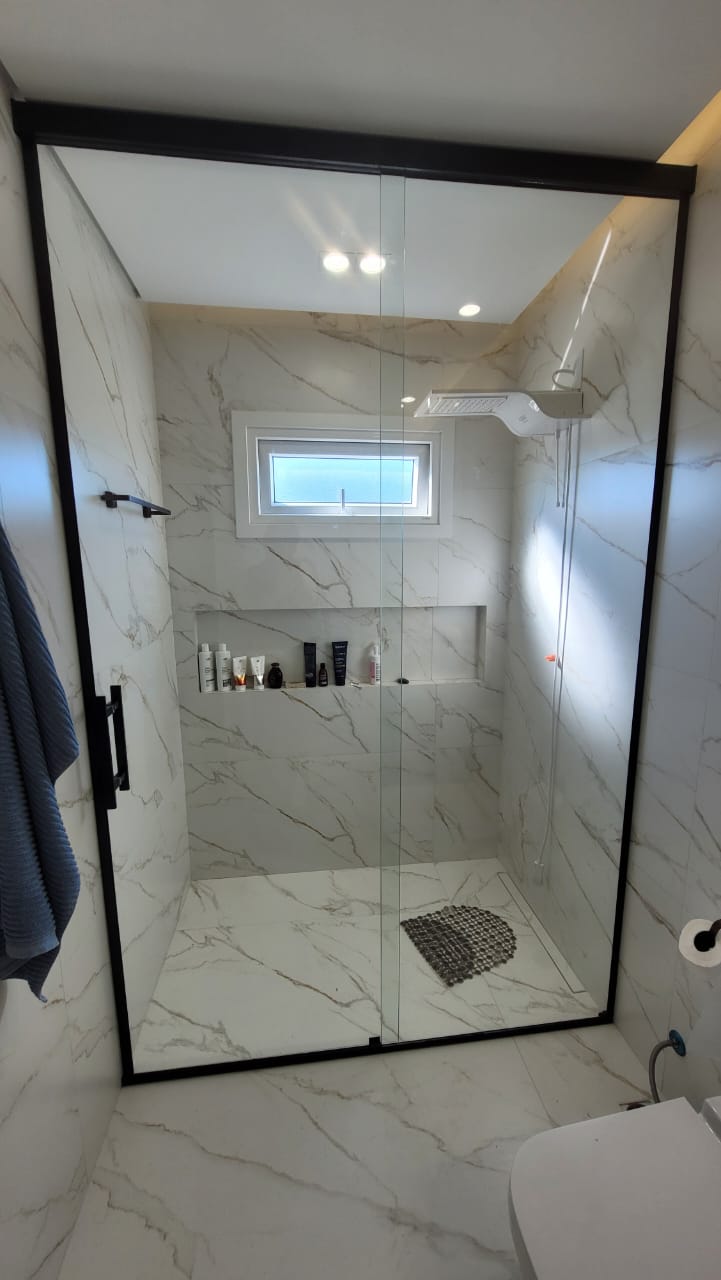 Box de vidro com perfil preto em banheiro de mármore branco